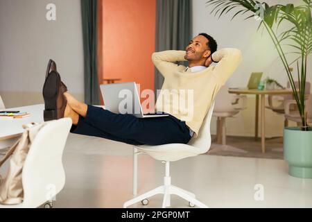 Thoughtful young businessman relaxing with feet up in office Stock Photo