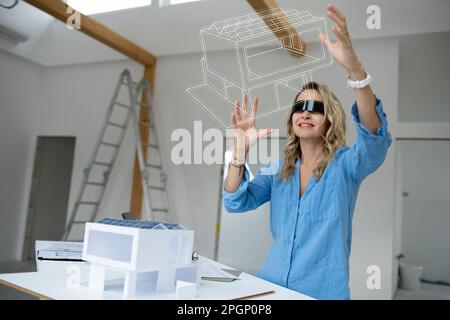 Architect wearing virtual reality simulator examining house model Stock Photo