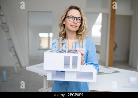 Architect holding model home standing at site Stock Photo