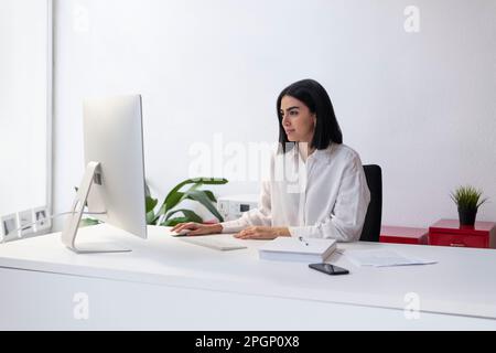 Businesswoman working on desktop PC at desk Stock Photo