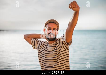Smiling man with hand raised wearing striped t-shirt Stock Photo