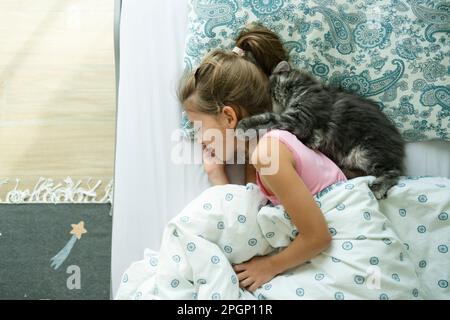 Sleeping girl with cat on bed at home Stock Photo