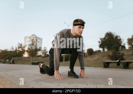 Determined man preparing for run on footpath Stock Photo