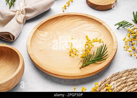 Composition with clean wooden dishes, napkin and mimosa flowers on white grunge table Stock Photo