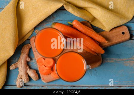 Two glasses of fresh carrot juice and ginger on blue wooden background Stock Photo