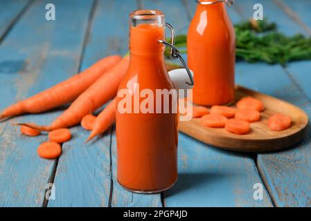 Two glass bottles of fresh carrot juice  on blue wooden background Stock Photo