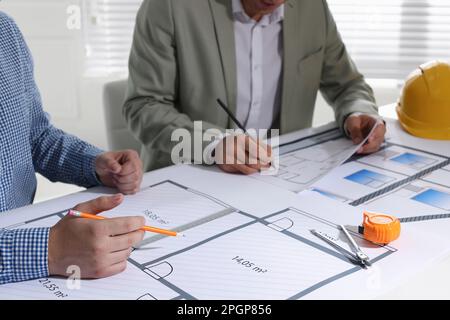 Architects working with construction drawings at table in office, closeup Stock Photo