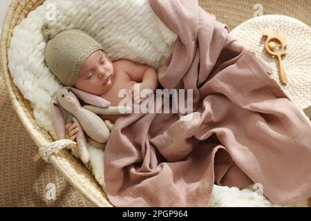 Cute newborn baby with toy bunny sleeping in cradle at home, top view Stock Photo