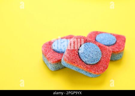 Dishwasher detergent tablets on yellow background, closeup. Space for text Stock Photo