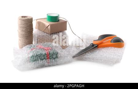 Cardboard boxes, bubble wrap, scissors and adhesive tape on white background Stock Photo