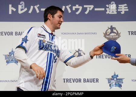 Trevor Bauer shows his new uniform and cap of Yokohama DeNA BayStars with  Tatsuhiro Hagiwara, left, senior director of Team Operations Department  during a photo session of the news conference Friday, March