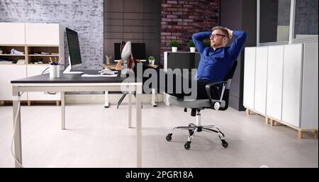 Advisor Man Relaxing In Office Chair At Desk Stock Photo