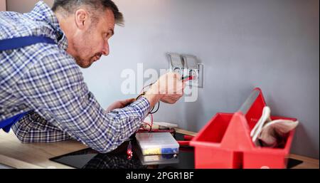Male Electrician Checking Voltage Of Socket With Multimeter In House Stock Photo