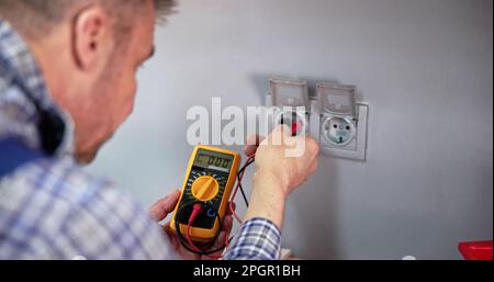 Male Electrician Checking Voltage Of Socket With Multimeter In House Stock Photo