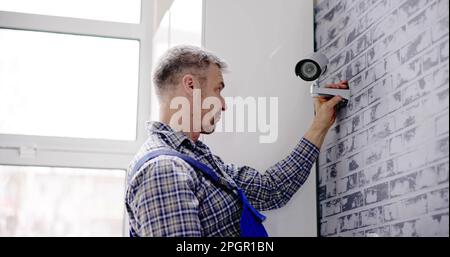 Close-up Of Technician Adjusting CCTV Camera On Wall Stock Photo