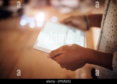 Productivity packed into one smart device. Closeup shot of an unrecognisable businesswoman using a digital tablet in an office at night. Stock Photo