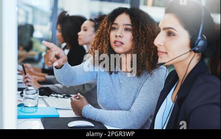 Direct the call over there...a young woman assisting her colleague in a call centre. Stock Photo