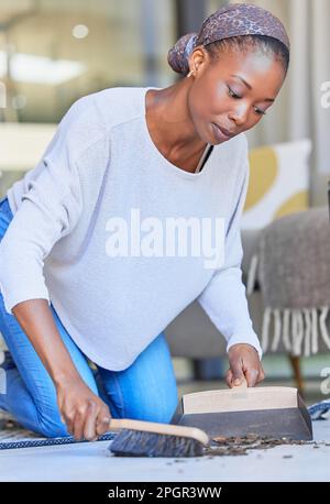 Maid, housekeeping and black woman cleaning and sweeping floor of a living room in a home or house for hygiene. Housekeeper, cleaner and domestic Stock Photo