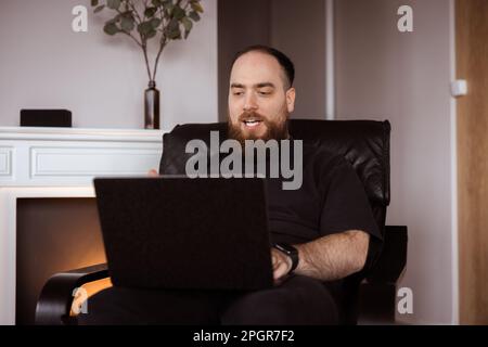 Man works from the comfort of his own home holding his laptop. Face expression of working remotely Stock Photo