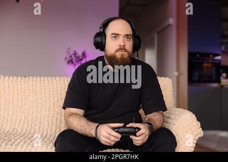 Male gamer playing video games with the controller in his hands. and his headsets on. Face expression of a gamer. Stock Photo