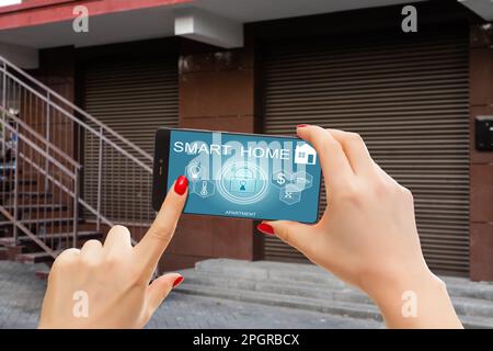 Cropped image of female entering secret key code for getting access and passing building using application on mobile phone, woman pressing buttons on Stock Photo