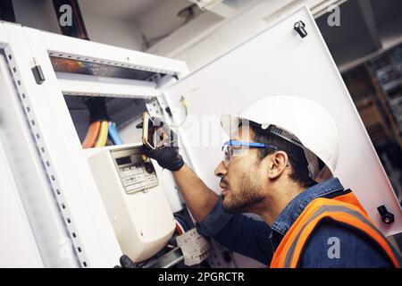 Man, phone and technician in electric inspection for power or sustainable energy at work site. Male electrician, contractor or engineer with Stock Photo