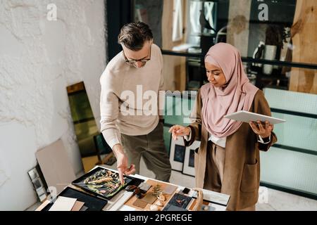 Two multiracial colleagues designers using tablet computer while working together in workshop Stock Photo