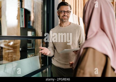 Two multiracial colleagues using tablet while working together in modern office Stock Photo