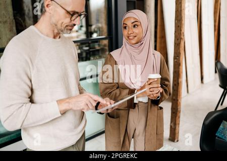 Two multiracial colleagues designers using tablet computer while working together in modern office Stock Photo