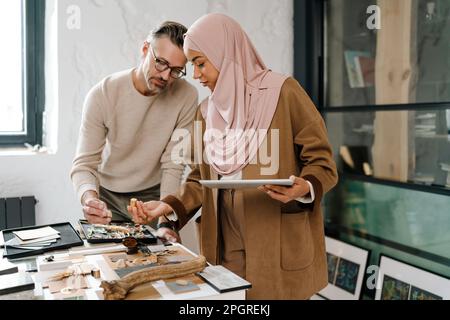 Two multiracial colleagues designers using tablet while working together in modern office Stock Photo