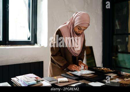 Female muslim architect wearing headscarf working on tablet in modern office Stock Photo