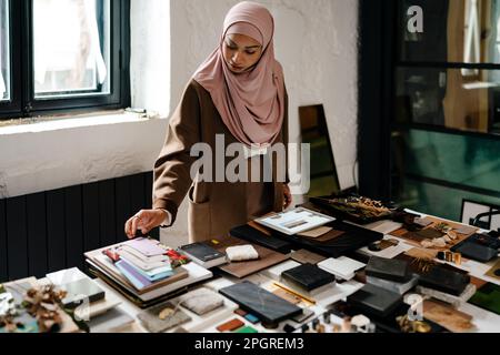 Female muslim architect wearing hijab working on tablet at workshop Stock Photo