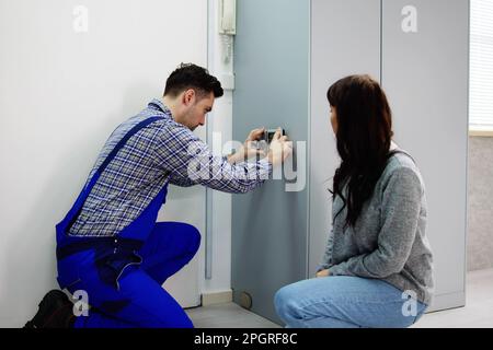 Alarm System Security Installation At Home. Technician Installing Near Door Stock Photo