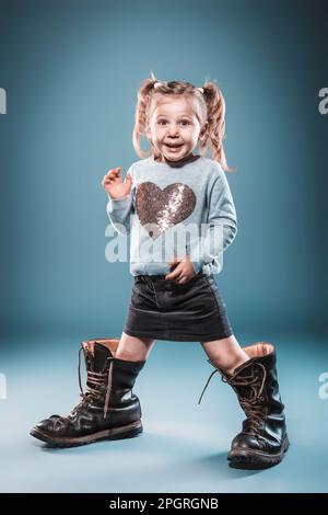 blonde girl plays with big boots. studio shot Stock Photo Alamy