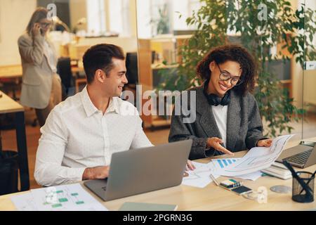 Two colleagues working together with documents while sitting on office desk. Teamwork concept Stock Photo