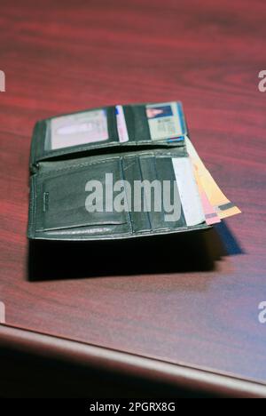 male leather wallet with money and id cards laying open on table Stock Photo