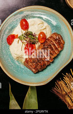 An artistic close-up of a plate of food featuring a steak and mashed potatoes Stock Photo
