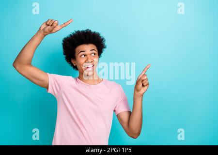 Photo of optimist promoter young guy indicate fingers mockup useful tips information looking interested isolated on aquamarine color background Stock Photo