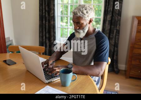 Senior african american man working from home sitting at the table using laptop. staying at home in isolation during quarantine lockdown. Stock Photo