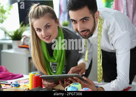 Woman and man stylist designers are holding tablet and discussing new clothes sketch Stock Photo