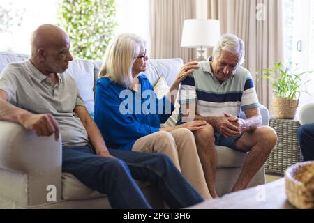 Group of diverse senior friends sitting in living room, talking in group therapy session. Senior lifestyle, friendship and support. Stock Photo