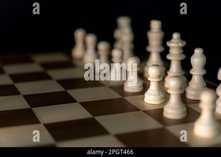 A closeup of a chessboard set up in its beginning position featuring classic white chess pieces Stock Photo