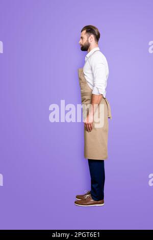 Full size fullbody, side view profile portrait snap of handsome attractive barber in uniform, isolated over grey background Stock Photo