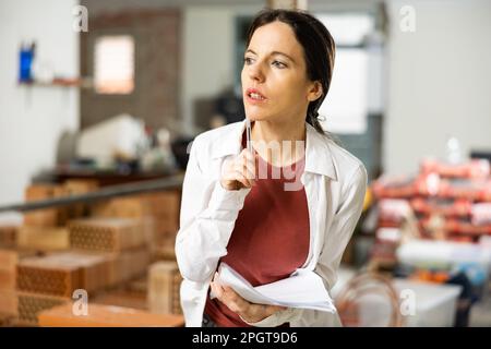 Interested brunette making notes while planning home renovation Stock Photo