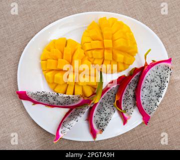 Slices of ripe juicy mango and pitaya on plate Stock Photo