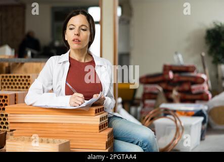 Interested brunette making notes while planning home renovation Stock Photo