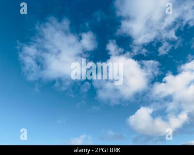 Bright blue sky with fluffy white clouds drifting across on a clear day Stock Photo