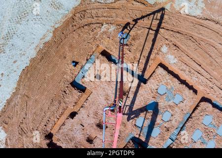 Construction worker using concrete pump to pour concrete into foundation of house Stock Photo