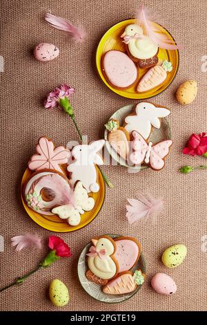 Decorated aesthetic Easter cookies, pink flowers with feathers and eggs. Spring pastel background. Stock Photo