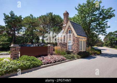 A beautiful landscaped divided entrance with brick pillars, guard house, flowers, sign and waterfall leading to an upscale housing community in a subu Stock Photo
